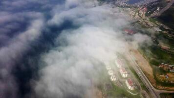 Drone view of the city by the sea. Part of the buildings is covered with fog. video