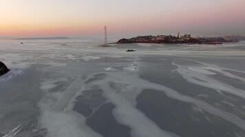Drone view of the ice-bound strait with two tugboats operating at sunset video