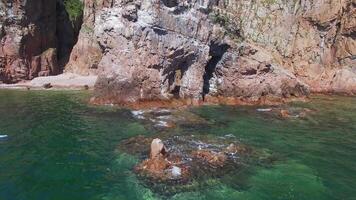Flight by drone from a stone arch on the seashore on a bright sunny day video