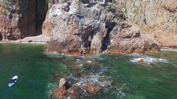 Flight by drone from a stone arch on the seashore on a bright sunny day video