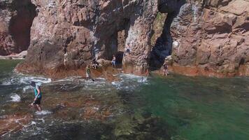 Flight by drone from a stone arch on the seashore on a bright sunny day video