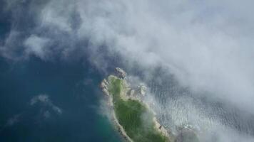 View from drone flying above the wooded rocky cape shrouded in fog video