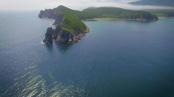 Drone view above the sea along the rocky coast and high cliffs on a sunny day. video