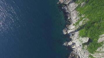 Drone view above the sea along the rocky coast and high cliffs on a sunny day. video