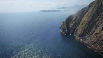 Drone view along the rocky coast and high cliffs on a sunny day shrouded in fog. video