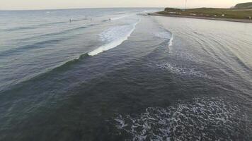 Drone view of surfers waiting for a wave in the sea at sunset video