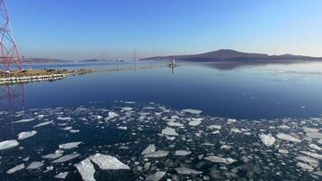 Drone view as a guy and a girl in winter wetsuits row on a sup among ice floes video