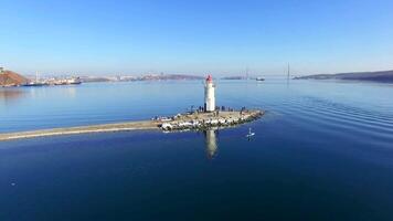 Drone view as a two guys in wetsuits row on a sup along the spit with lighthouse video