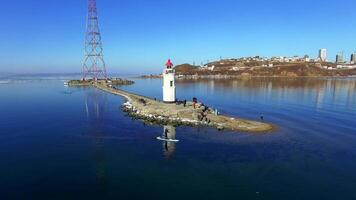 Drone view as a guy in wetsuits row on a sup along the spit with lighthouse video