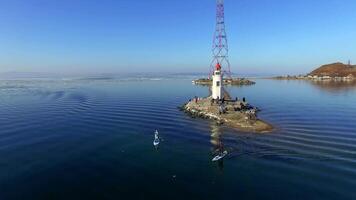 Drone view as a guy and girl in wetsuits row on a sup along the lighthouse video