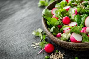 Fresh colorful salad with various vegetables and herbs placed on wooden surface photo