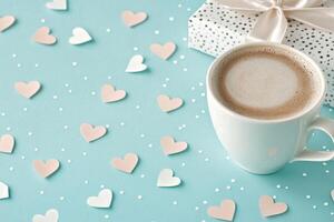 A cup of coffee with a heart design in the foam sits on a small plate photo