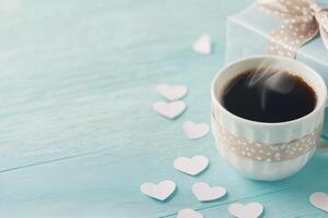 A cup of coffee with a heart design in the foam sits on a small plate photo