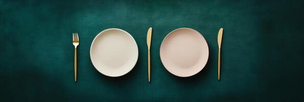 Elegant table setting with gold cutlery and simple dishes on dark green background photo