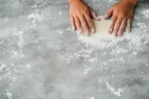 Making dough on a clean surface with hands covered in flour during baking preparation photo