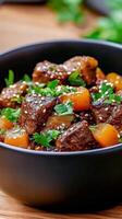 Delicious beef stew with vegetables served in a black bowl at a cozy kitchen setting photo