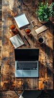 Workspace with laptop, coffee, and plants on wooden table in natural light photo