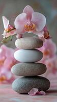 Balanced stones with pink orchids on reflective surface in tranquil setting by water photo