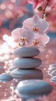Balanced stones with pink orchids on reflective surface in tranquil setting by water photo