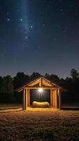 Starry night over a rustic shelter with hay under a glowing light in the countryside photo