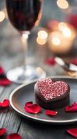 Romantic dessert with heart shaped cake and wine on a table decorated with rose petals photo