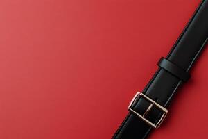 Black leather belt on a solid red background showcasing classic style and elegance in accessories photo