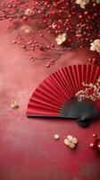 Beautiful red fan rests on a vibrant surface with decorative branches in the background photo
