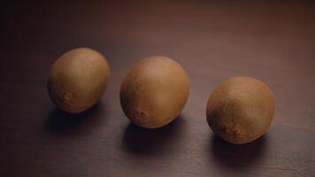 Three ripe Kiwi Fruits arranged on a rustic Wooden Surface, showcasing their vibrant color video
