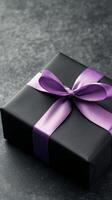 Elegant black gift box with purple ribbon wrapped on textured background photo