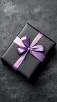 Elegant black gift box with purple ribbon wrapped on textured background photo