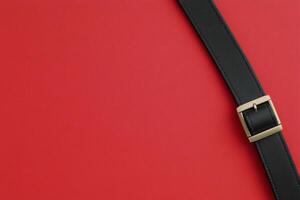 Black leather belt on a solid red background showcasing classic style and elegance in accessories photo