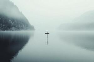 Reflections on calm waters with a cross in the distance at dawn photo