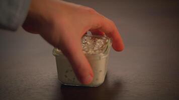 A Hand Holding a Small Container Gently Resting on a Textured Surface in a Calm Setting video