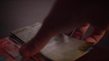 A Hand Holding a Brightly Colorful Banknote While Resting on a Rustic Wooden Surface video