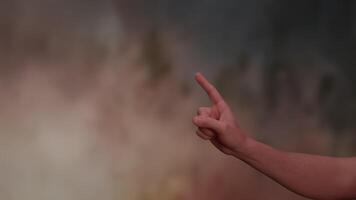A human hand performing a pointing gesture against an abstract and artistic background video