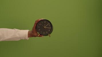A Hand is Holding a Vintage Clock Against a Soft Green Background for Visual Appeal video