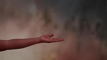 A Hand Gently Reaching Out Against a Softly Colored and Dreamy Background of Warm Tones video