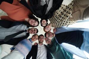 A diverse group of business professionals standing together in a powerful, united pose, captured from a low-angle perspective, exuding confidence and teamwork photo