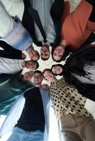A diverse group of business professionals standing together in a powerful, united pose, captured from a low-angle perspective, exuding confidence and teamwork photo
