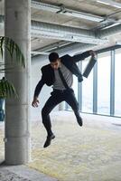 A businessman ecstatically jumping in a modern office, holding a briefcase in his hands, celebrating a moment of success and triumph. photo