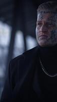A mysterious man adorned with tattoos stands confidently in an intriguing urban setting video