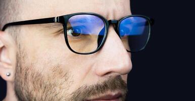 The face of a young man in glasses looking at the monitor. Close-up. Banner. Copy space. Selective focus. photo