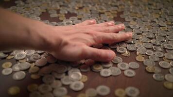 Gently and intentionally placing various coins on a surface of a table during a casual setting video