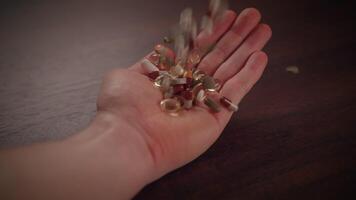 The image depicts a hand holding a variety of different pills, supplements, and capsules video