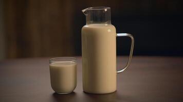 A pitcher and a glass filled with fresh milk are elegantly presented on a wooden table video