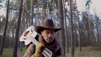 A backpacker with a guitar walks along a trail in the forest. Travel concept. Close-up Slow motion video