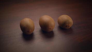 There are Three Kiwi Fruits beautifully arranged on a Wooden Surface for you to see and enjoy video