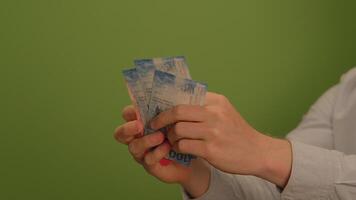Hands counting cash on a green background, highlighting financial activities and transactions video