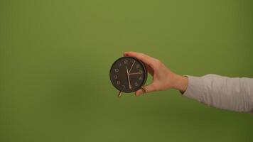 A Hand Holding a Clock Against a Beautiful Green Background for Visual Impact and Appeal video