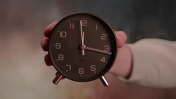 A Classic Alarm Clock is held in hand against a beautifully soft and calming background video